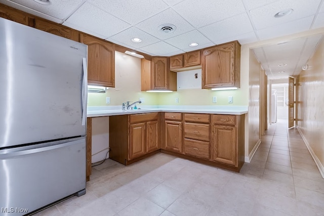 kitchen featuring brown cabinetry, visible vents, baseboards, freestanding refrigerator, and light countertops