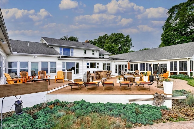 rear view of house with a deck and outdoor dining space