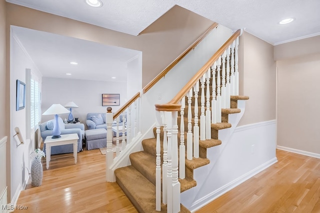 stairs with crown molding, recessed lighting, wood finished floors, and baseboards