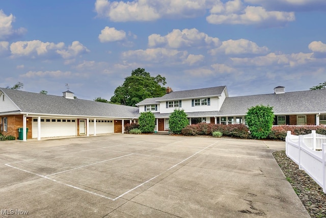 view of front of property with brick siding, an attached garage, a shingled roof, fence, and driveway