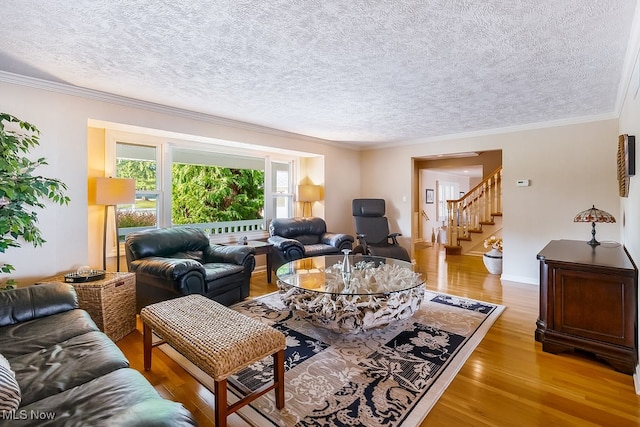 living room with a textured ceiling, stairway, crown molding, light wood finished floors, and baseboards