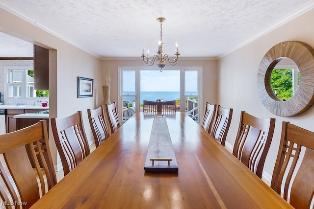 dining area with a notable chandelier, a textured ceiling, crown molding, and baseboards