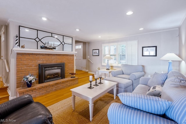 living room with light wood finished floors, recessed lighting, a brick fireplace, and ornamental molding