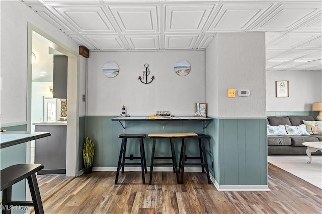 kitchen with wood finished floors, a wainscoted wall, and an ornate ceiling