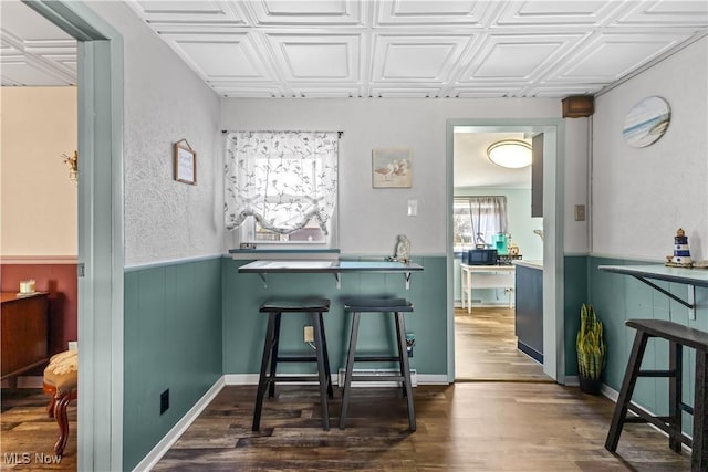 dining area featuring wainscoting, an ornate ceiling, and dark wood-style flooring