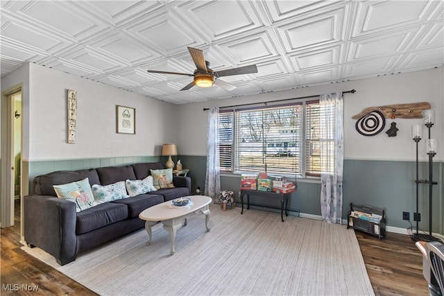 living area with an ornate ceiling, baseboards, ceiling fan, and wood finished floors