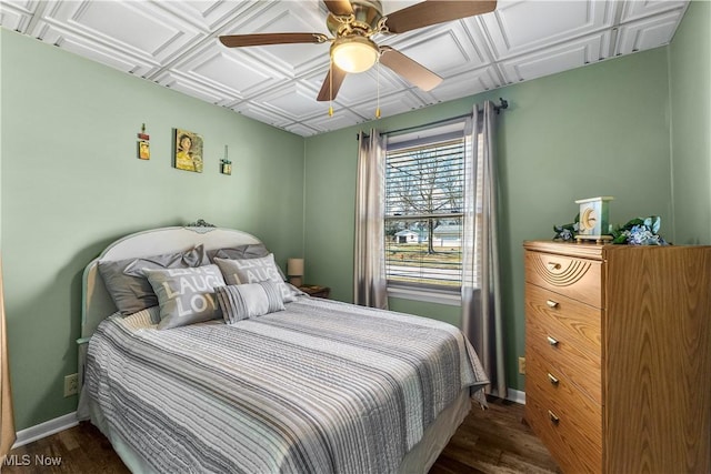 bedroom with dark wood-style flooring, a ceiling fan, baseboards, and an ornate ceiling