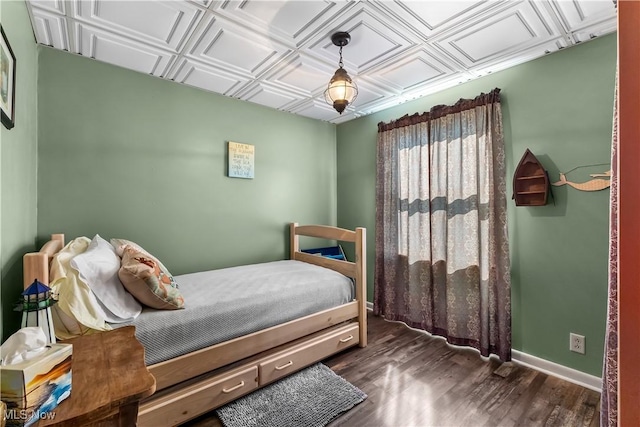 bedroom featuring an ornate ceiling, baseboards, and wood finished floors