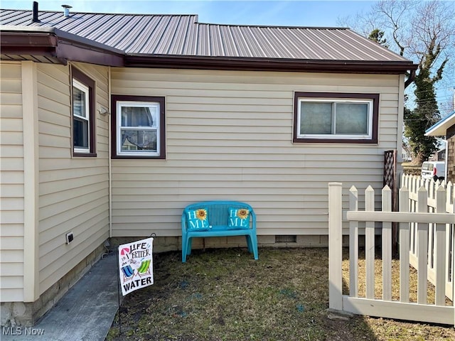 view of home's exterior with crawl space, metal roof, and fence