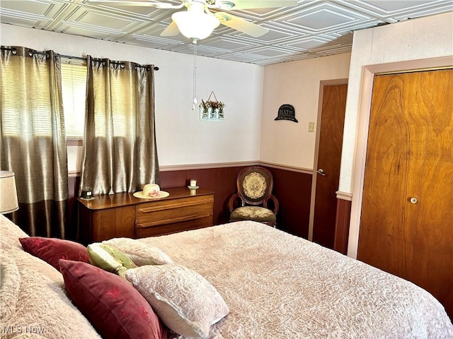 bedroom with an ornate ceiling, ceiling fan, and wainscoting