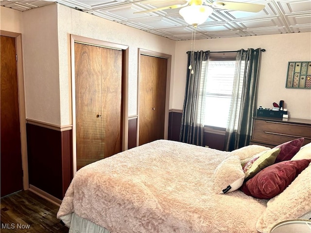 bedroom with dark wood-style floors, an ornate ceiling, multiple closets, and a textured wall