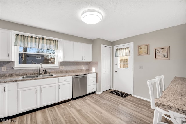 kitchen with a sink, light wood-type flooring, stainless steel dishwasher, and a wealth of natural light