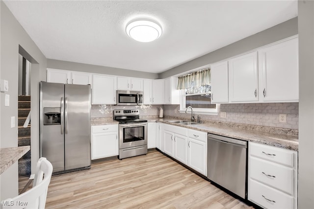 kitchen featuring a sink, light wood-style flooring, appliances with stainless steel finishes, and white cabinets