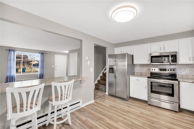 kitchen with decorative backsplash, white cabinetry, light wood finished floors, and stainless steel appliances