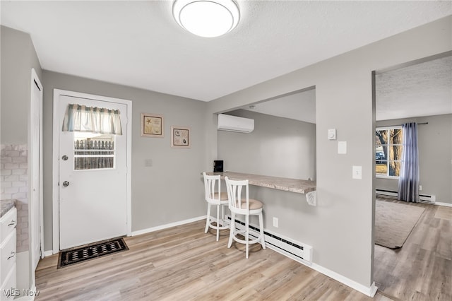 dining room with baseboards, a wall mounted air conditioner, baseboard heating, wood finished floors, and a textured ceiling