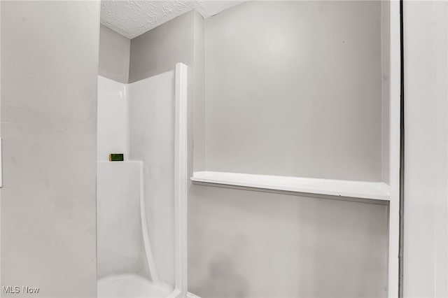 full bathroom featuring a shower and a textured ceiling