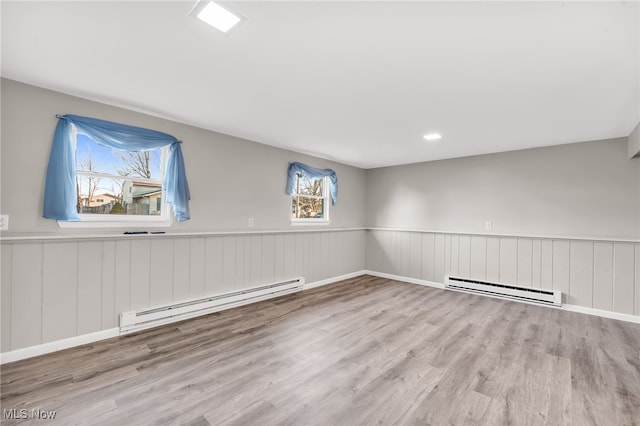 spare room featuring wood finished floors, wainscoting, and a baseboard radiator