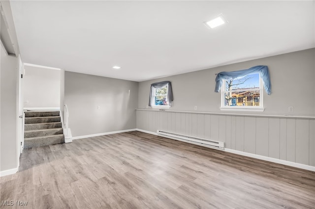 below grade area featuring stairway, wood finished floors, baseboards, and baseboard heating