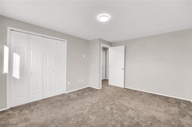 unfurnished bedroom featuring a closet, baseboards, and carpet