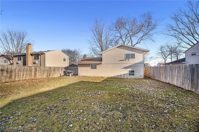 rear view of house featuring a yard and a fenced backyard