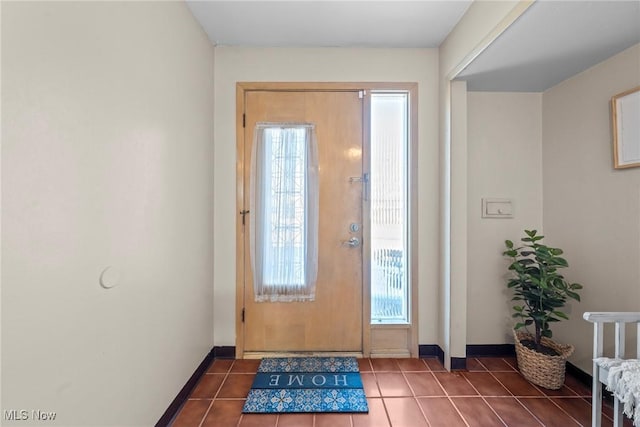 foyer entrance featuring dark tile patterned floors and baseboards