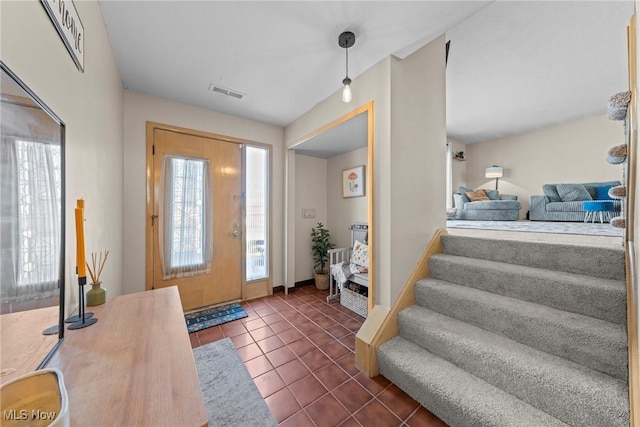 entrance foyer featuring stairs, dark tile patterned flooring, and visible vents