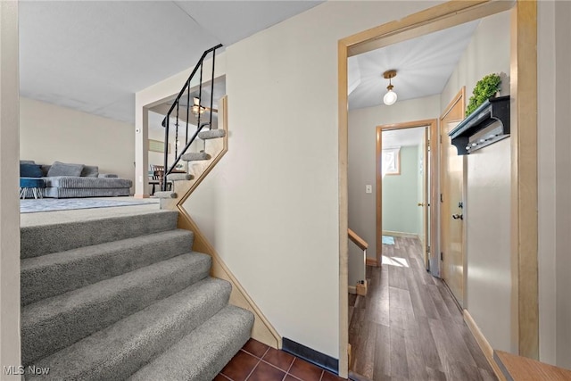 staircase featuring baseboards and wood finished floors