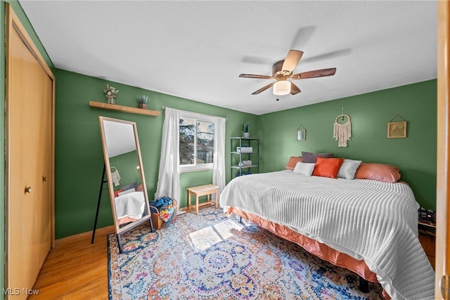 bedroom with a ceiling fan, light wood-style floors, a closet, and baseboards