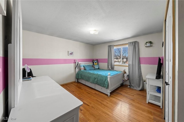 bedroom with light wood-style floors and a textured ceiling