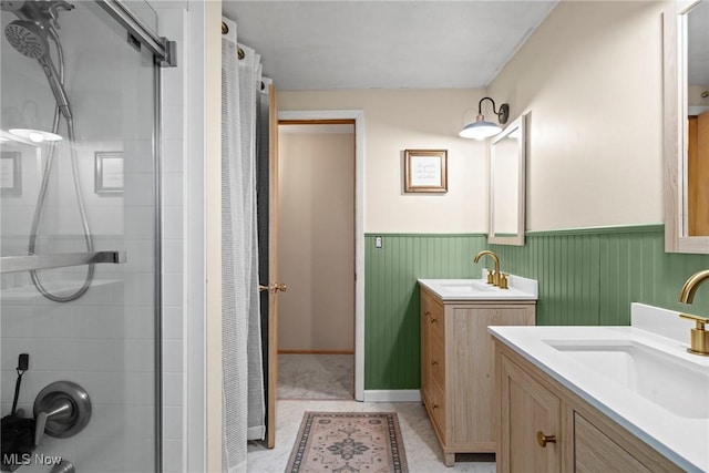 bathroom featuring a sink, a shower with shower door, and wainscoting