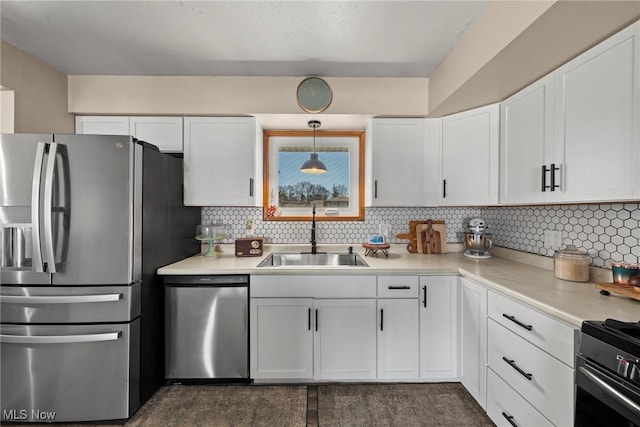 kitchen with a sink, decorative backsplash, light countertops, stainless steel appliances, and white cabinetry