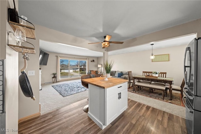 kitchen featuring wooden counters, dark wood finished floors, open floor plan, freestanding refrigerator, and white cabinets