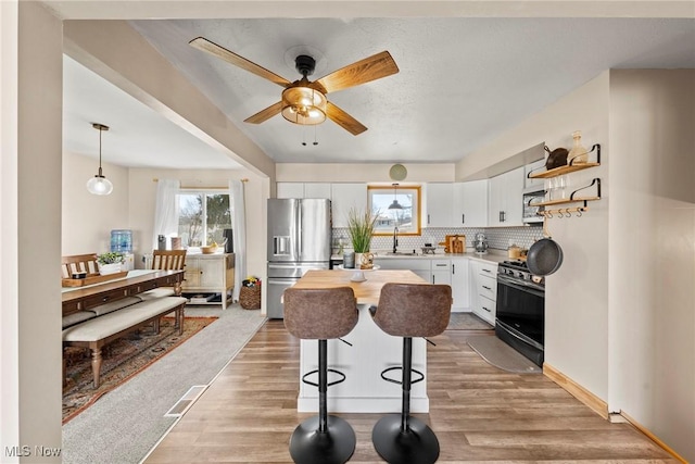 kitchen with tasteful backsplash, a healthy amount of sunlight, white cabinets, and stainless steel appliances