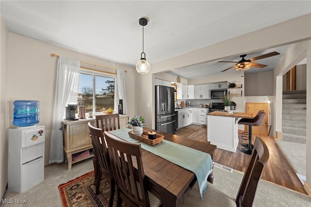 dining space with ceiling fan, wood finished floors, and stairs