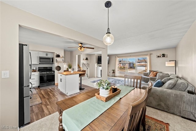 dining space with stairway, wood finished floors, and ceiling fan