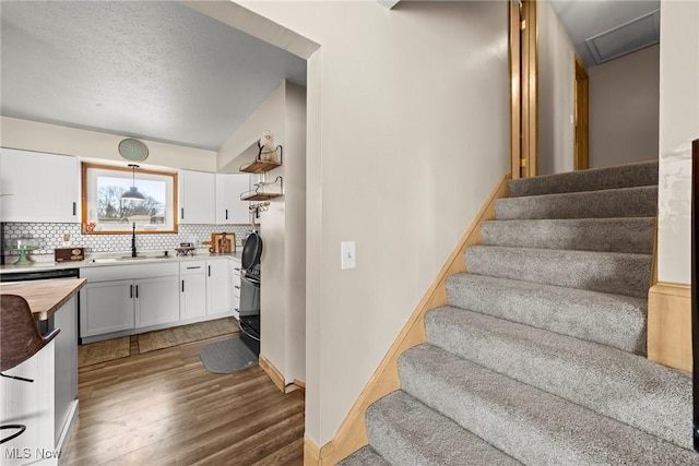 staircase featuring wood finished floors, baseboards, and a textured ceiling