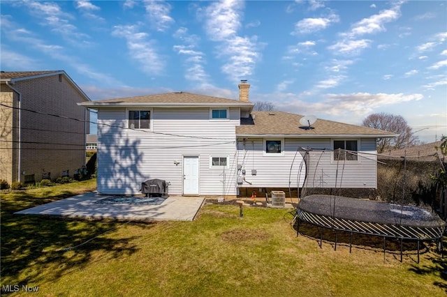 rear view of property with a patio, a trampoline, a yard, and a chimney