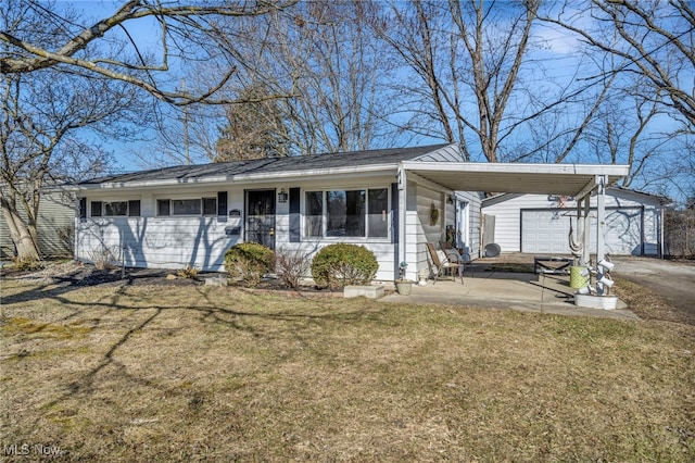 single story home featuring an attached carport, an outbuilding, a front yard, driveway, and a garage