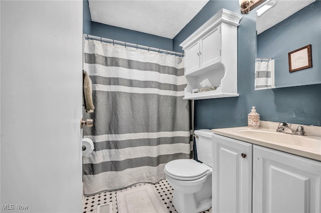 bathroom with visible vents, toilet, vanity, and a textured ceiling