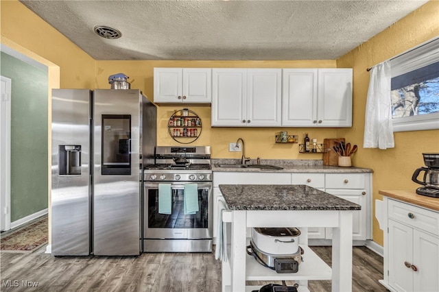 kitchen with light wood finished floors, visible vents, appliances with stainless steel finishes, and white cabinetry