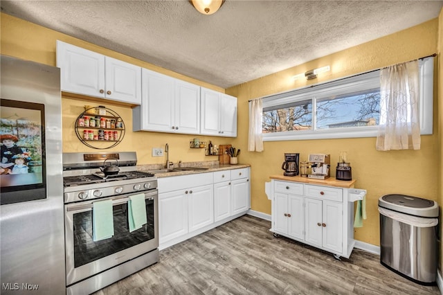 kitchen with a sink, stainless steel appliances, white cabinetry, and light countertops