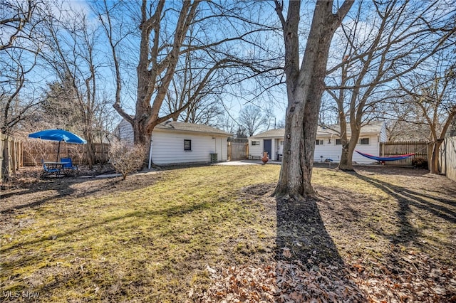 view of yard featuring a patio area, a fenced backyard, and an outbuilding