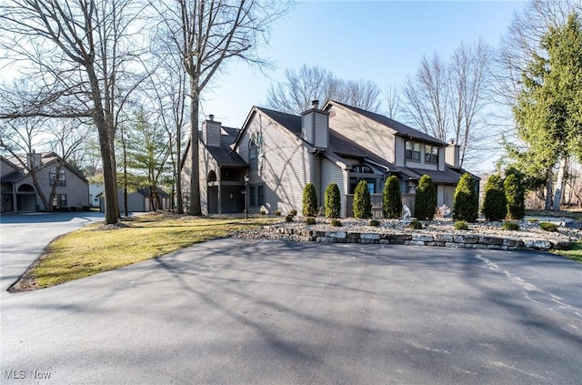 view of home's exterior featuring driveway and a chimney