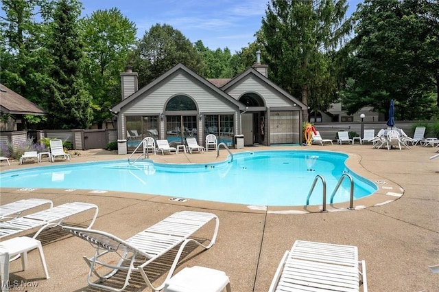 community pool with a patio and fence