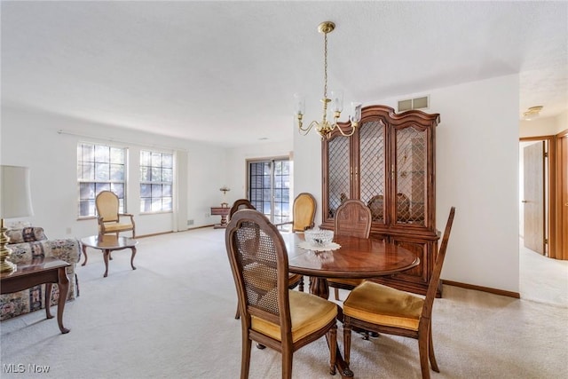 dining room featuring light carpet, visible vents, baseboards, and a notable chandelier