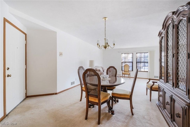 dining space featuring a notable chandelier, light colored carpet, visible vents, and baseboards