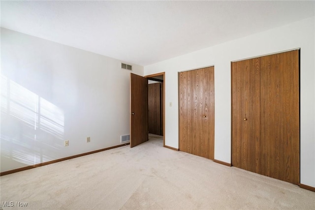 unfurnished bedroom with visible vents, multiple closets, carpet floors, and baseboards