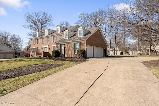 view of front of home with a garage, brick siding, concrete driveway, and a front yard