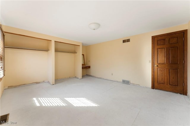 unfurnished bedroom with visible vents and multiple closets