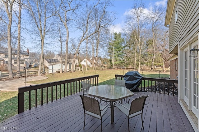 deck featuring outdoor dining space, a yard, a residential view, and grilling area